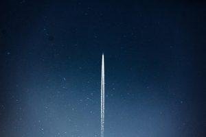 A rocket streaks through a starry night, leaving a trail in outer space.