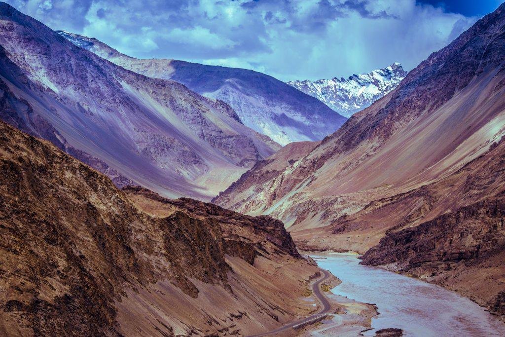 Majestic view of a Himalayan valley with winding river beneath dramatic clouds.