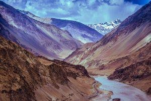 Majestic view of a Himalayan valley with winding river beneath dramatic clouds.